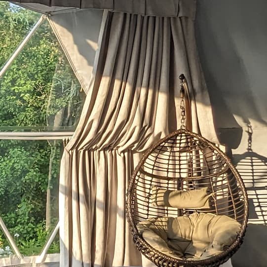Full-height curtains hanging inside a furnished Luna dome