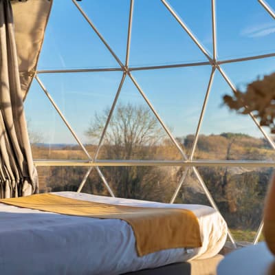 Framed panoramic glazing beside a bed inside a Luna dome
