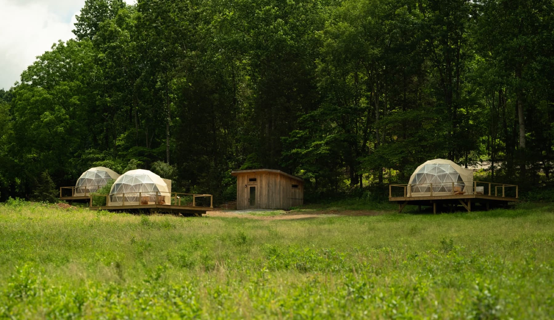 Several glamping structures in an open field